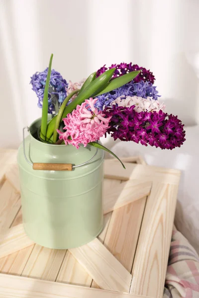 Beautiful hyacinths in metal can on wooden crate indoors. Spring flowers — Stock Photo, Image