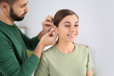 Genç kadının kulağına kapalı koyarak işitme cihazı adam