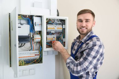 Elektrikçi içeride tornavidayla sigorta kutusunu tamir ediyor.