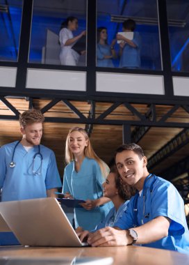 Group of smart medical students with gadgets in college clipart