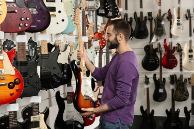 Alıcı modern müzik mağazasında gitar seçimi