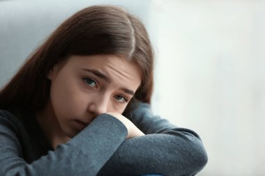 Upset teenage girl on blurred background. Space for text