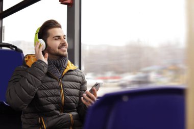 Genç adam toplu taşıma kulaklıklar ile müzik dinleme