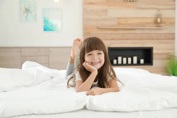 Χαριτωμένο μικρό κορίτσι ξαπλωμένο στο κρεβάτι στο σπίτι — Φωτογραφία Αρχείου