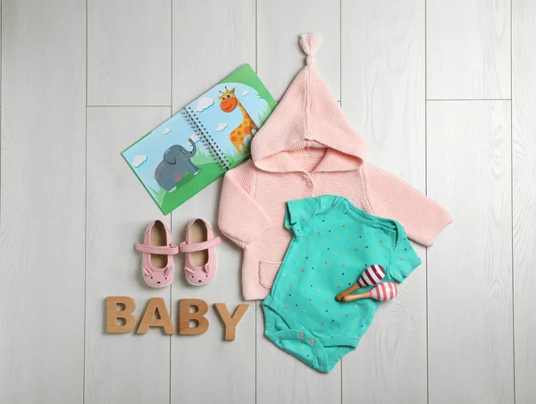 Composición plana con ropa linda sobre fondo de madera. Accesorios para bebés — Foto de Stock
