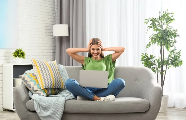 Érzelmi fiatal nő, laptop ünnepli győzelmét a kanapén, otthon — Stock Fotó