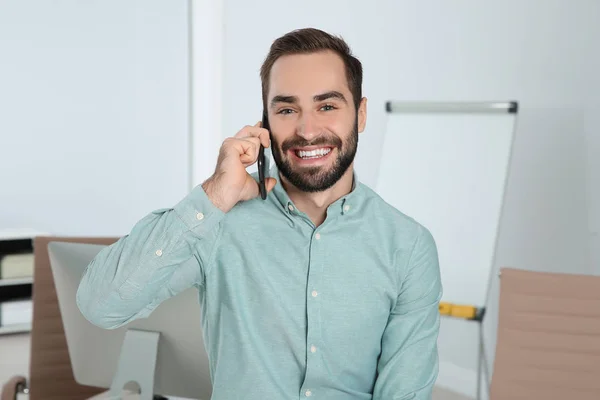 Mladý muž se smíchem, když mluví o telefonu v kanceláři — Stock fotografie