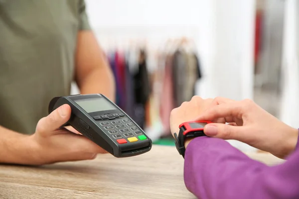 Vrouw met terminal voor contactloze betaling met smart watch in de winkel, close-up — Stockfoto