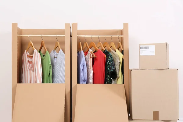 Wardrobe boxes with clothes on light background