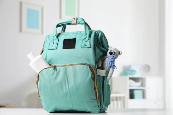 Tas ransel dengan aksesoris bayi di atas meja di dalam ruangan. — Stok Foto