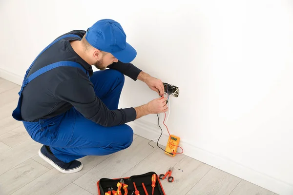 Eletricista com testador de verificação de tensão dentro de casa, espaço para texto — Fotografia de Stock