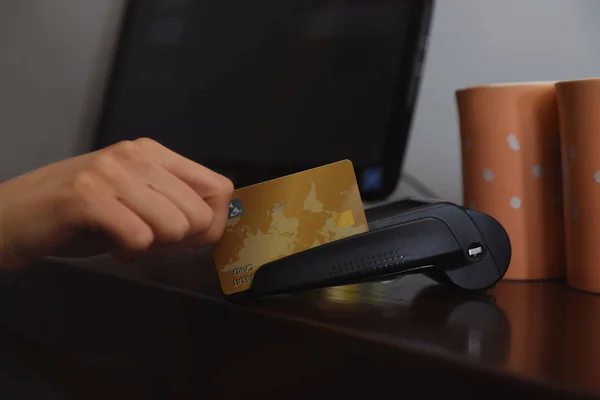 Woman using credit card machine for non cash payment in cafe, closeup