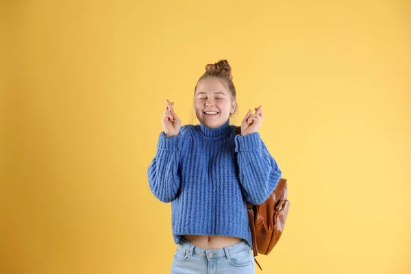 Bastante adolescente con mochila cruzando los dedos sobre fondo de color —  Fotos de Stock