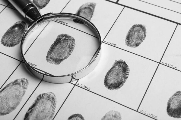 Magnifying glass and criminal fingerprint card, closeup