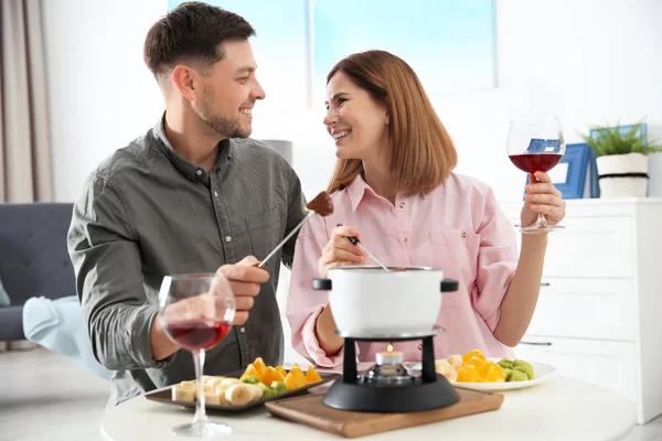 Šťastný pár, kteří požívají fondue večeře doma — Stock fotografie