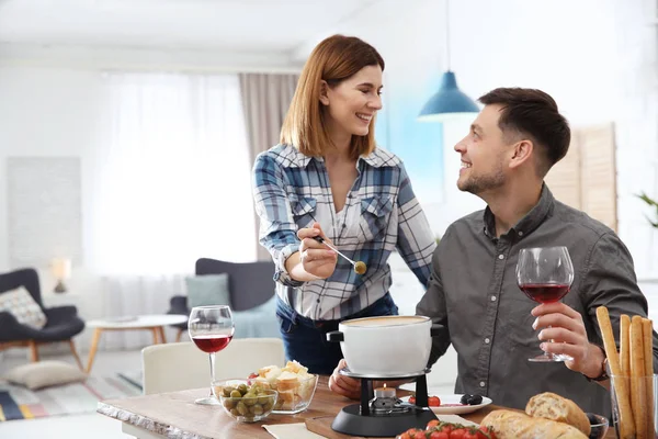 Šťastný pár, kteří požívají fondue večeře doma — Stock fotografie