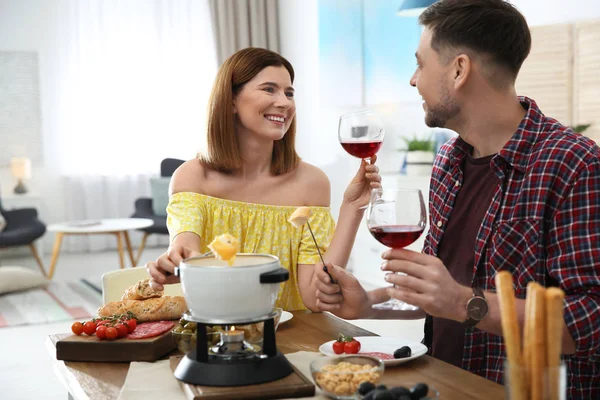 Šťastný pár, kteří požívají fondue večeře doma — Stock fotografie