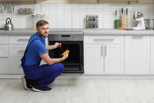 Profesjonalny serwisant naprawy nowoczesnego pieca w kuchni — Zdjęcie stockowe