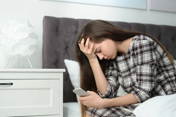 Ideges tizenéves lány okostelefon ül az ágyban. Szóköz a szöveghez — Stock Fotó