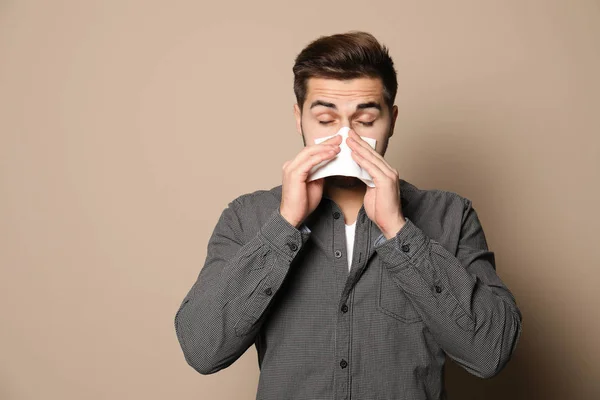 Joven guapo sonándose la nariz contra el fondo de color. Espacio para texto — Foto de Stock