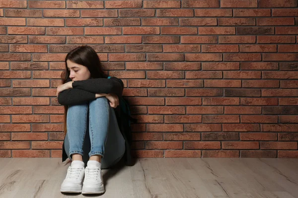 Αναστατωμένος έφηβο κορίτσι κάθεται στο πάτωμα κοντά στον τοίχο. Χώρος για κείμενο — Φωτογραφία Αρχείου