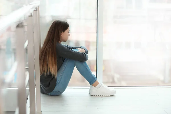 O adolescentă supărată stând la fereastră în interior. Spațiu pentru text — Fotografie, imagine de stoc