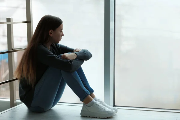 Aufgebrachte Teenager, die drinnen am Fenster sitzen. Raum für Text — Stockfoto