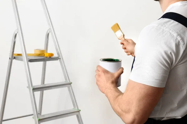 Decorador masculino con pincel y lata de pintura en interiores, primer plano. Espacio para texto — Foto de Stock