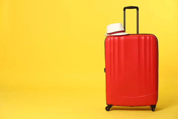 Bright suitcase with hat on color background. Space for text — Stock Photo, Image