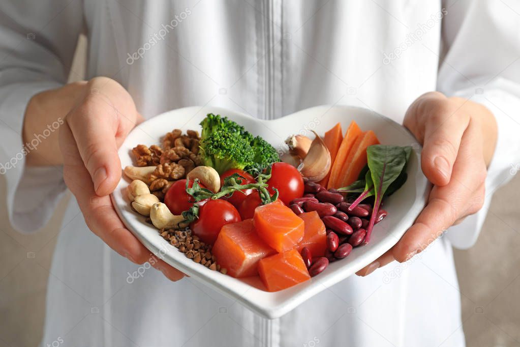 Doctor holding plate with products for heart-healthy diet, closeup