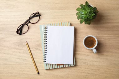 Tahta arka planda defter, kahve ve bardaklarla düz kompozisyon