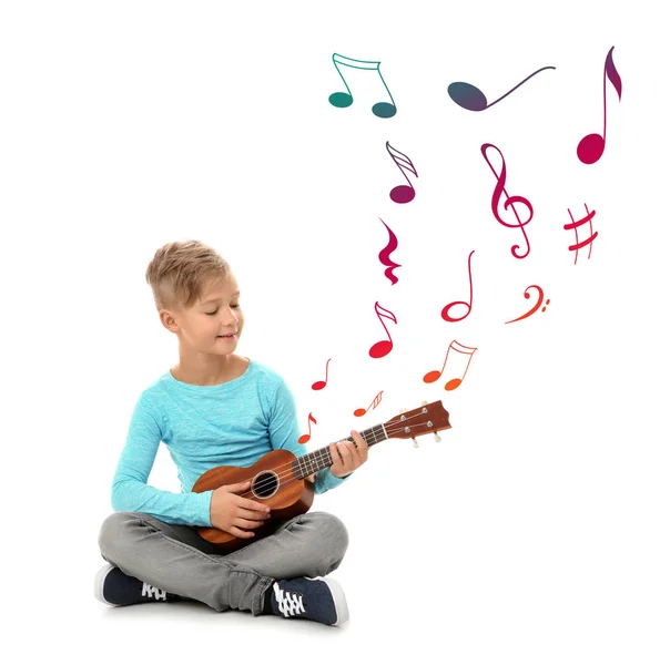 Liten pojke som spelar gitarr och flygande noter på vit bakgrund — Stockfoto