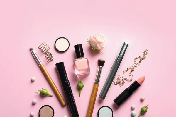 Flat lay composition with products for decorative makeup on pastel pink background