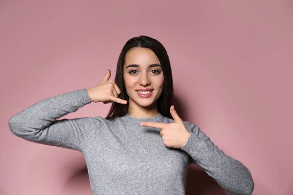 Mujer mostrando LLAME gesto en lenguaje de señas sobre fondo de color —  Fotos de Stock