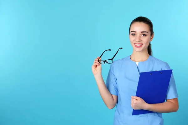 Ung medicinsk student med Urklipp och glasögon på färg bakgrund. Utrymme för text — Stockfoto