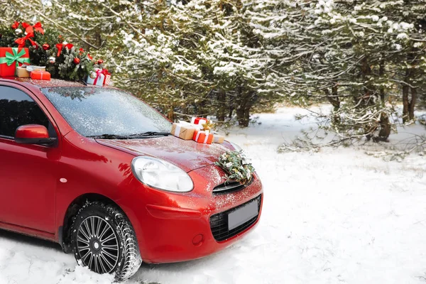Autó-koszorú, karácsonyfa, ajándékok téli napon a havas erdőben — Stock Fotó