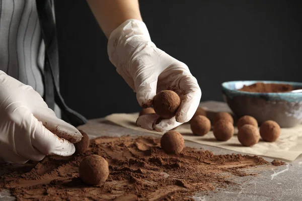 Женщина готовит вкусные шоколадные трюфели за столом, крупным планом — стоковое фото