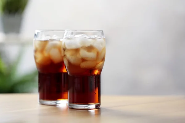 Óculos de cola com gelo na mesa contra fundo desfocado, espaço para texto — Fotografia de Stock