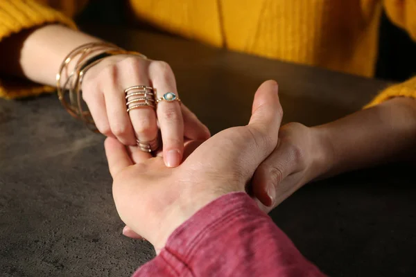 Chiromancer reading lines on man's palm at table, closeup — ストック写真