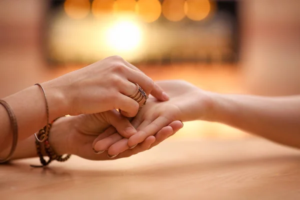 Chiromancer reading lines on woman's palm at table, closeup — Stock Photo, Image