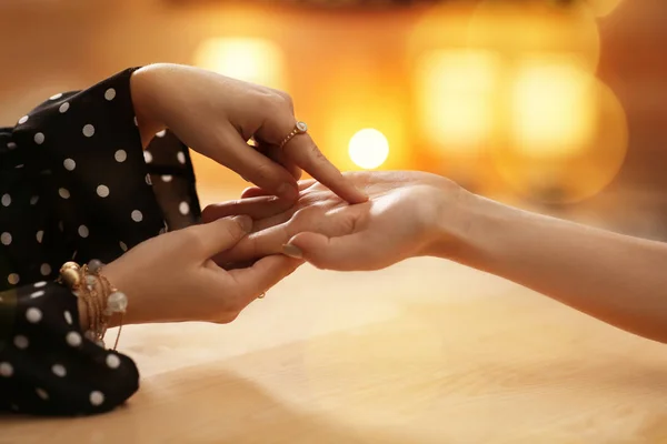 Chiromancer reading lines on woman's palm at table, closeup — Stock Photo, Image