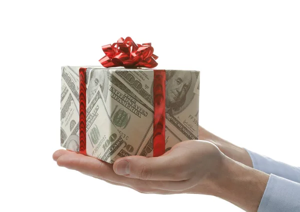 Hombre sosteniendo caja de regalo envuelta en papel decorativo con patrón de dólar sobre fondo blanco, primer plano — Foto de Stock