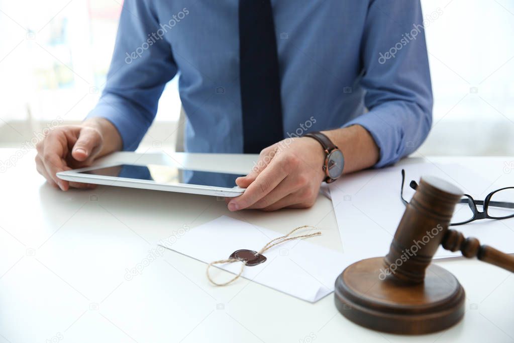 Notary working with tablet and judge gavel on table, closeup. Law and justice concept