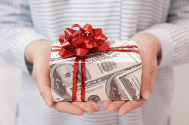 Kadın tutan hediye kutusu dolar, closeup sarılmış