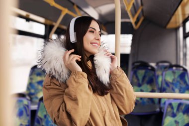 Genç kadın toplu taşıma kulaklıklar ile müzik dinleme