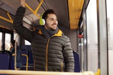 Genç adam toplu taşıma kulaklıklar ile müzik dinleme
