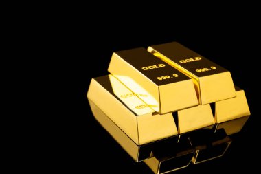 Siyah arka planda parlak altın çubuklar yığını. Metin alanı