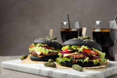 Masada servis edilen siyah Burger ve içecekler ile Board