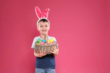 Renk arka plan, metin için yer üzerinde küçük çocuk bunny kulaklar kafa bandı holding sepeti ile Paskalya yumurta