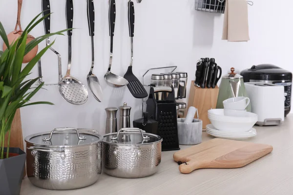 Set of clean cookware, dishes, utensils and appliances on table at white wall — Stock Photo, Image